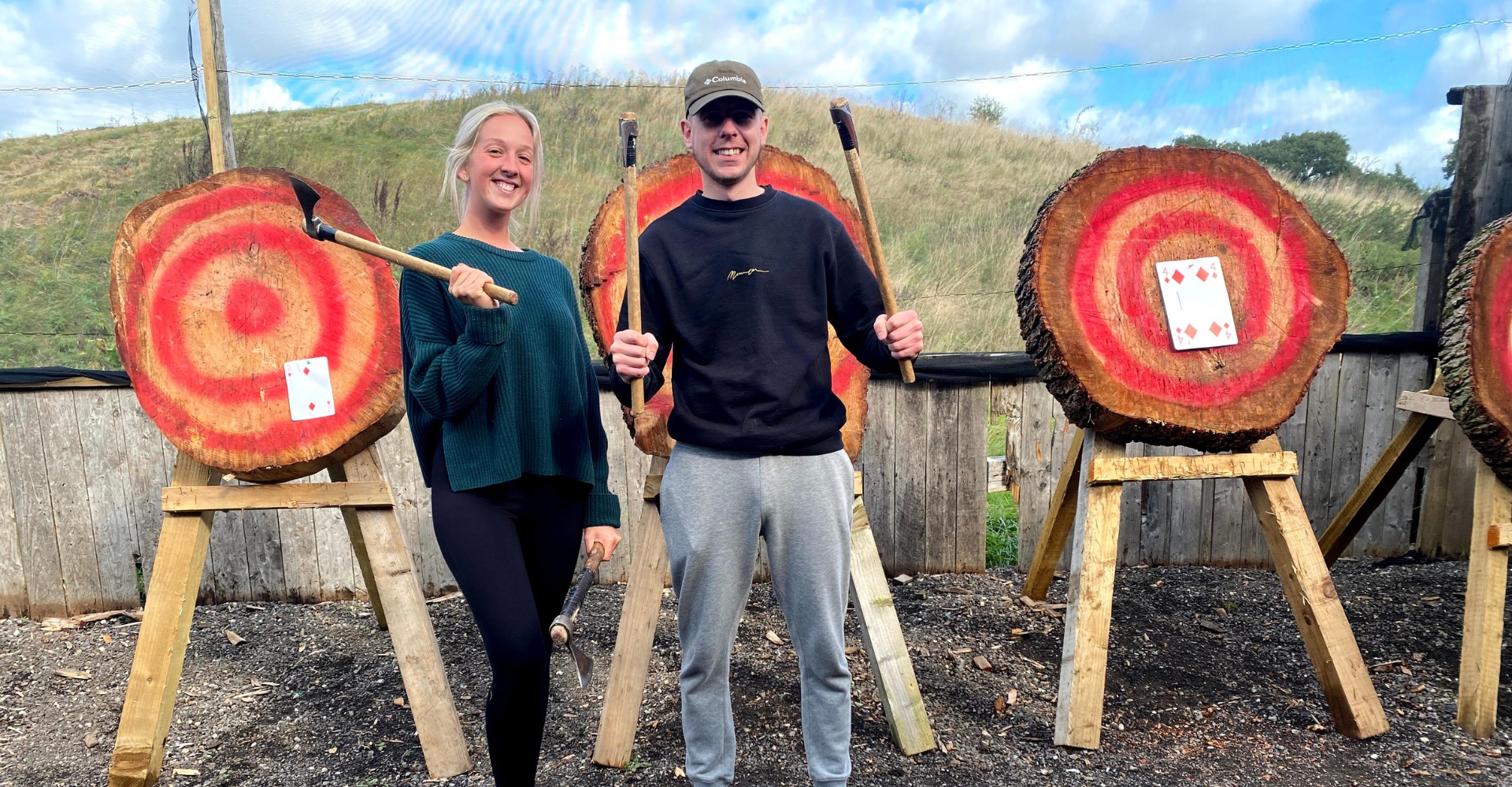 Happy customers at outdoor axe throwing range with targets